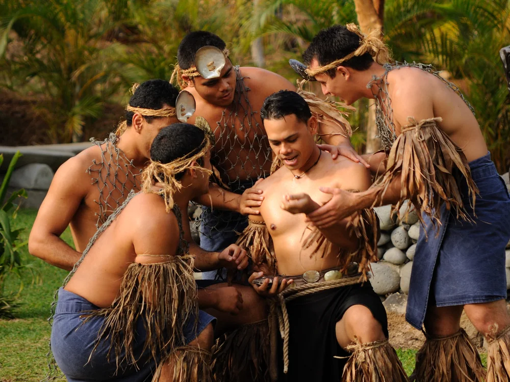 A group of male performers in traditional Tahitian dress gathered in a circle at the Polynesian Cultural Center's Tahiti village